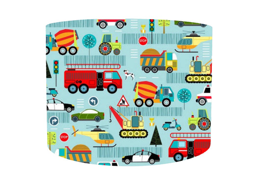 Transport themed drum lampshade.mDifferent types of transportation such as fire engine, trucks, helicopter, tractor set on a pale blue background. Front view