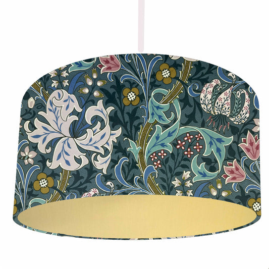 William Morris Golden Lily drum lampshade in heritage blue with floral pattern and gold lining on a white background